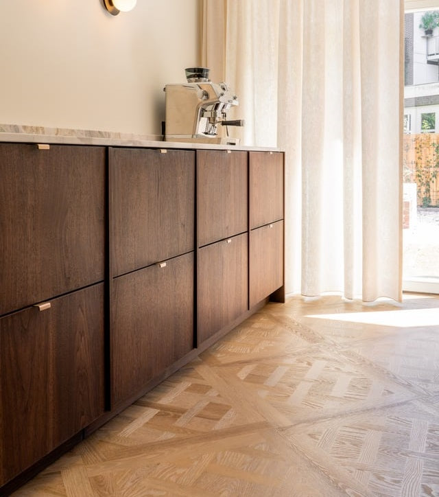 Keuken met donkere fineerkasten, een espressomachine en een Versailles-vloer